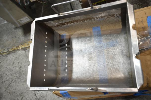 Stainless steel fryer insert with perforated sides, used condition, features handles for easy lifting, set on a wooden pallet.