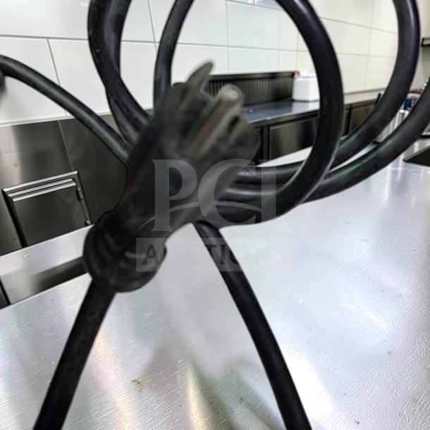 Coiled black power cord of the OBEL Mito ATR M64 commercial coffee grinder, indicating a 120V connection, photographed in a kitchen setting.