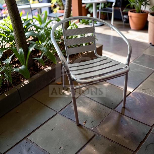 Silver Lancaster Table & Seating Outdoor Arm Chair, commercial-grade steel, stackable, in exceptional condition.