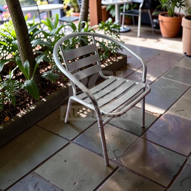 Stackable outdoor armchair by Lancaster Table & Seating, silver powder-coated steel, commercial-grade, excellent condition.