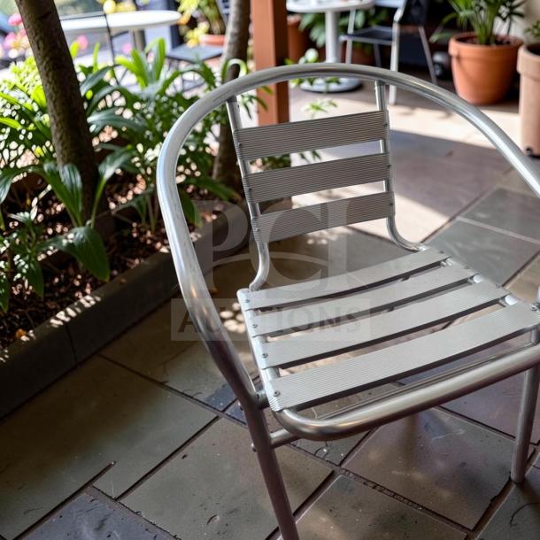 Lancaster Table & Seating outdoor arm chair, silver powder-coated steel, stackable, in excellent condition, commercial grade.
