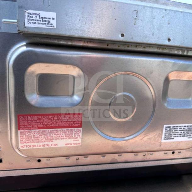 Sharp R-21LCFS Commercial Microwave Oven in stainless steel, showing label with safety warnings. Fully tested, 1000W, 120V.