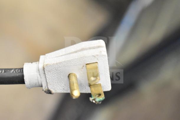 Close-up of a three-prong electrical plug connected to a True GDM-41SL-48-HC-LD cooler, showing 125 volts on the plug.