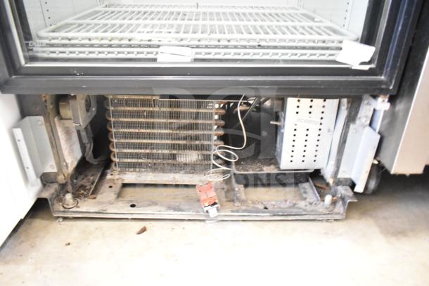 True GDM-12 Single Door Reach In Cooler; 115 Volts, 1 Phase. Visible cooling components, shelves inside; some wear.