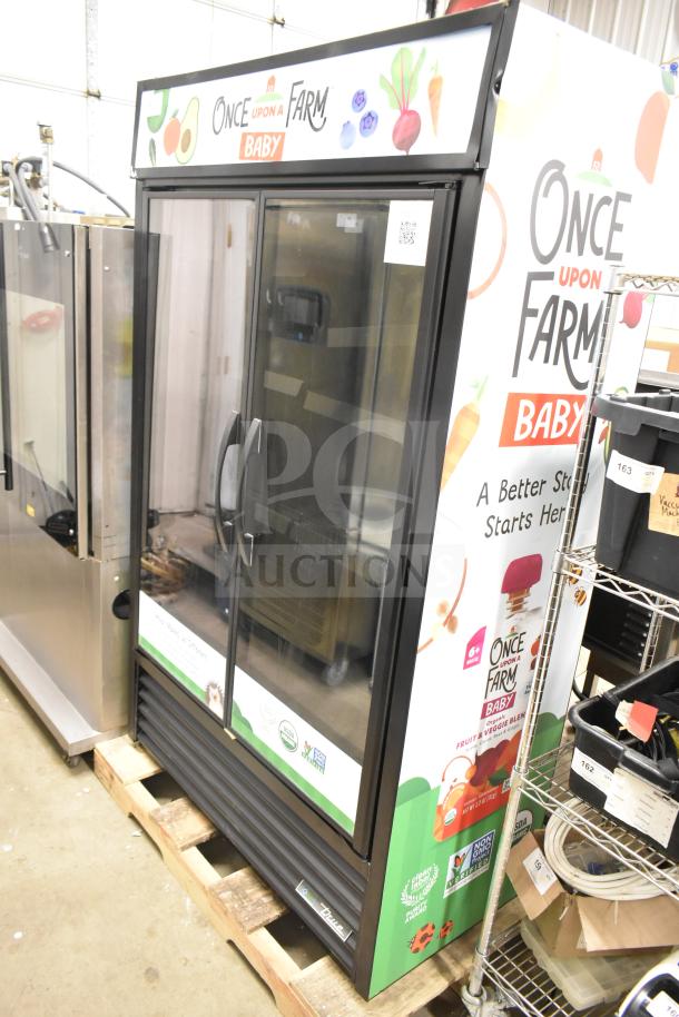 True TVM-48SL-HC commercial 2-door reach-in cooler merchandiser on a pallet. Branding reads "Once Upon a Farm Baby."