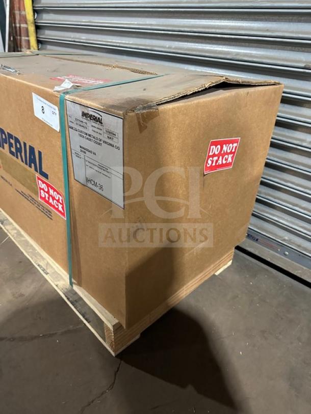 "New Imperial IHCM36 cheese melter in box. Features stainless steel, natural gas, infrared burner. Marked 'Do Not Stack.'"