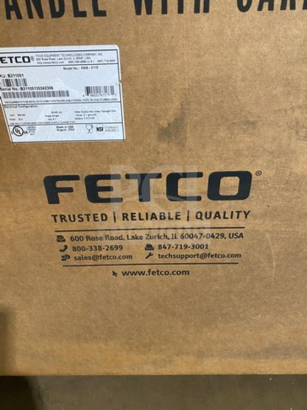 Brand new Fetco HWB-2110 10-gallon hot water dispenser in box. Visible logos and contact info indicate trusted quality.
