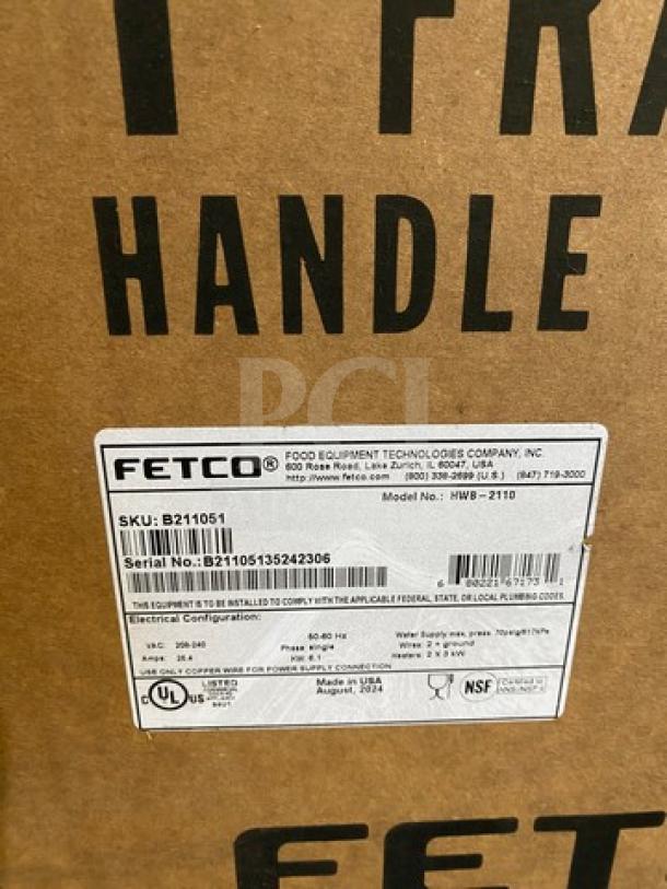 Brand new Fetco HWB-2110 10-gallon hot water dispenser in box. Label shows model HWB-2110, serial number, and certifications.