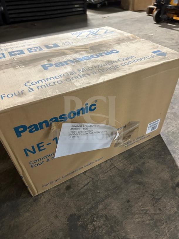Brand new Panasonic NE-1054F commercial microwave oven in box. Features touch pad, 115V, 1 phase, model label visible.
