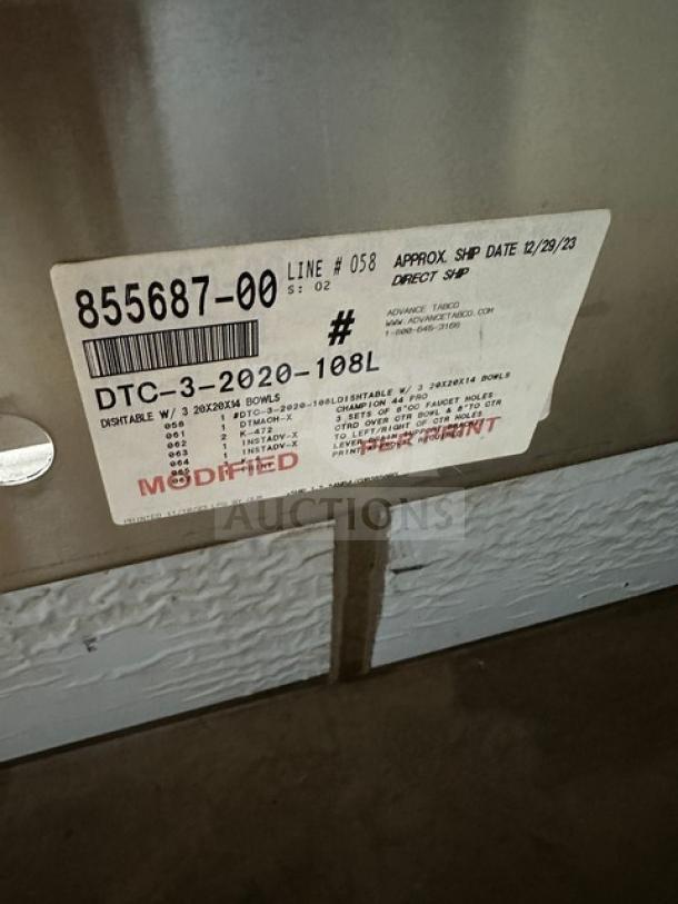 Brand new Advance Tabco stainless steel 3-compartment sink, model DTC-3-2020-10BL. Features a left side drain board. Shipping label with model and shipment details visible.