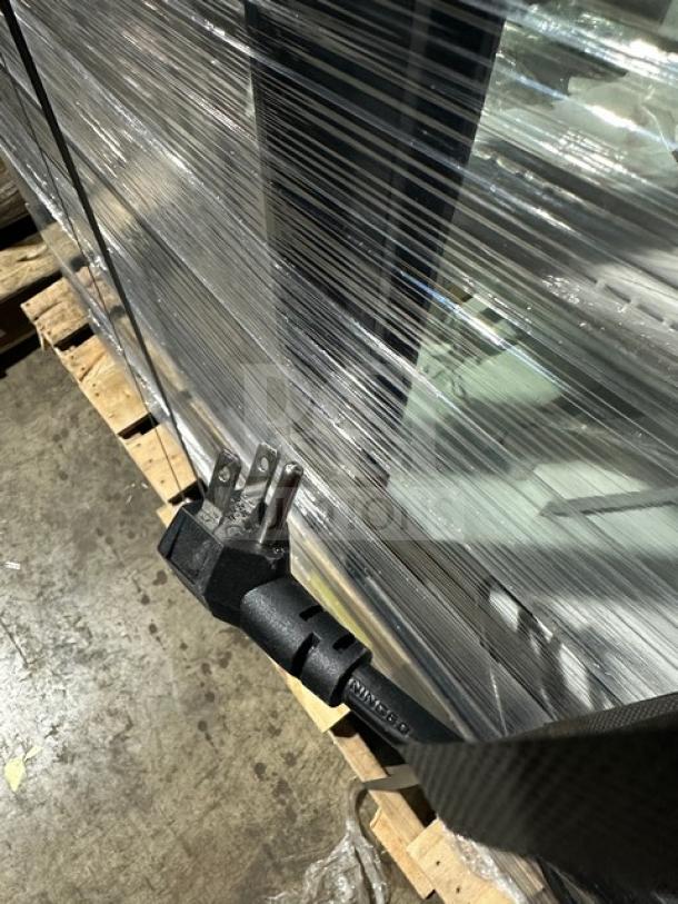 Beverage Air commercial refrigerator wrapped in plastic, showing a power cord, stored on a wooden pallet.