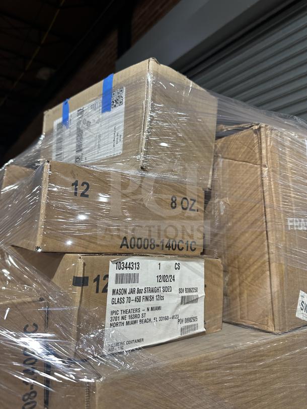 Stacked cardboard boxes on a pallet wrapped in plastic, labeled with shipping details, part of a new mixed auction lot.