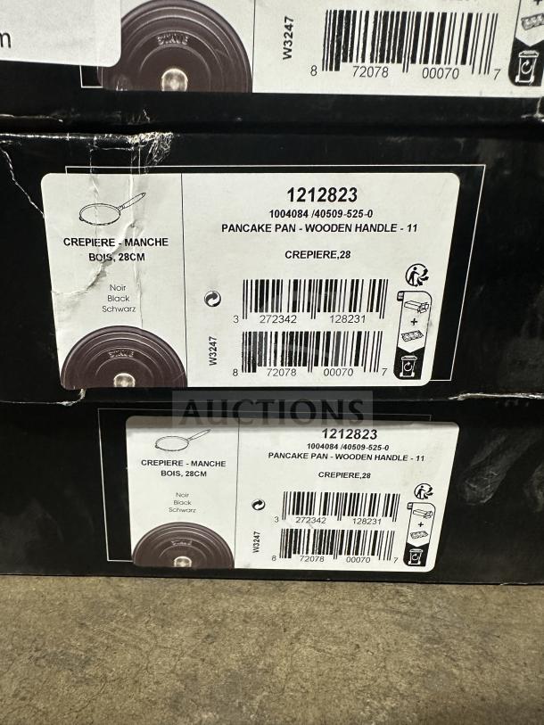 Brand new Staub Crepiere 28 CM cast iron pancake pan, black, with wooden handle. Model: CREPIERE.28. Box label visible.