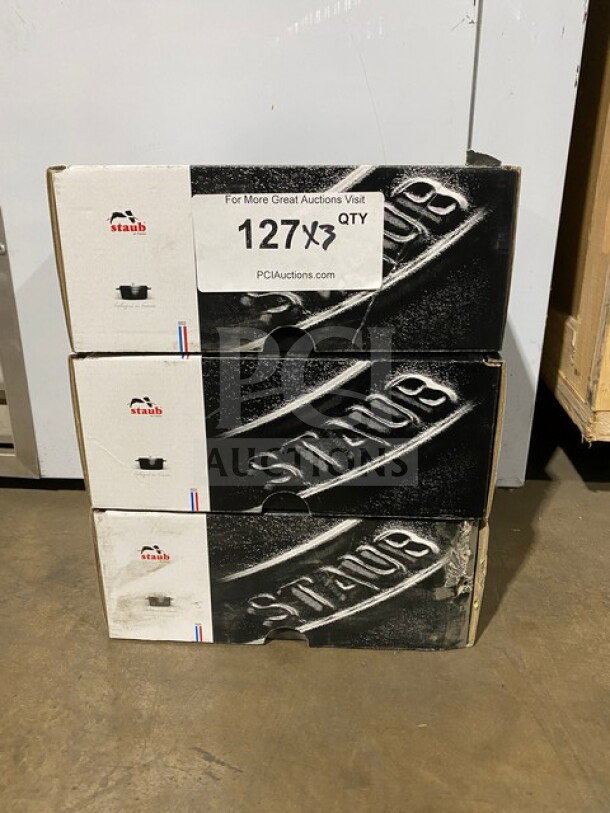 Brand new Staub Round Cocotte Pot Model 1101225 in sealed boxes, stack of three. Auction sign reads "3 X Your Bid!"