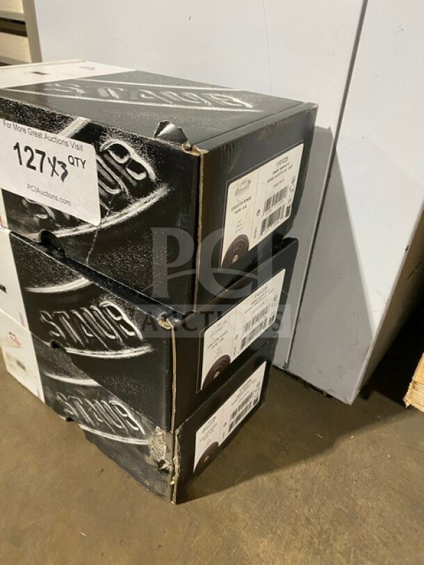 Brand new Staub round cocotte pot, model 1101225, in original box. Heavy-duty, durable design. Tags indicate auction details.