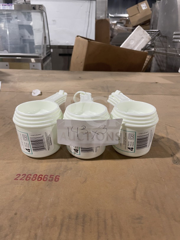 Brand new Winco commercial white measuring cup set, model L38315A0WHT, on display. Visible barcode and model label.