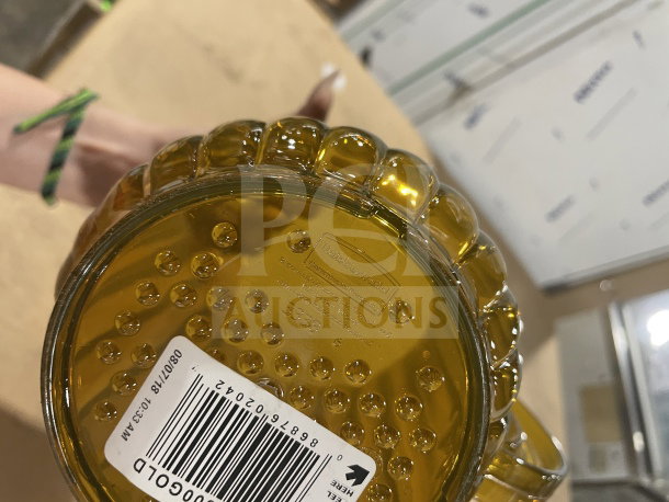 Brand new Rubbermaid Commercial gold beverage pitcher, model FG333800GOLD, clear glass with embossed logo and barcode tag.