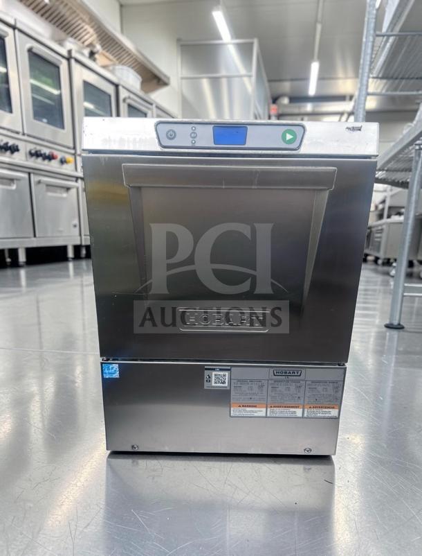 Outstanding condition Hobart LXEC-3 undercounter commercial dishwasher. Features: 34 racks/hour, low temp sanitizing, 120V, fully tested. Visible labels: Hobart branding, operational instructions.