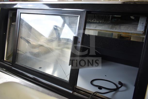 Torrey TEC130L-UL deli display case, 127V, 1 phase, floor style, visible crack in glass, black frame, interior view.