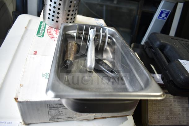 Lot of kitchen items including a perforated utensil holder, stainless steel bin with serving spoons, and a metal handle component.