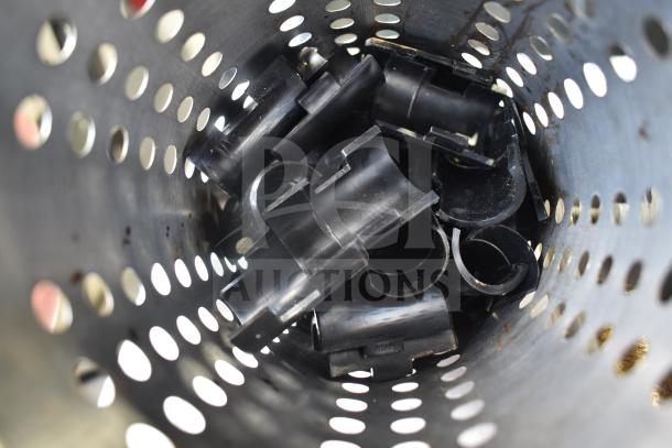A perforated metal bin containing black plastic clips. Condition appears used. Part of a lot including various items.