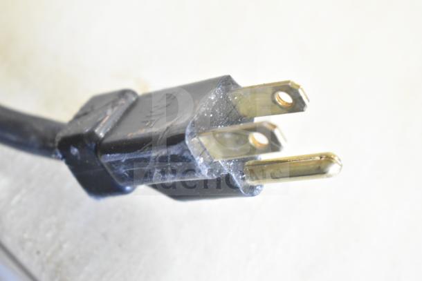 A close-up of a standard three-prong electrical plug showing minor wear, suitable for the Edesa EDST-48-12 prep table.