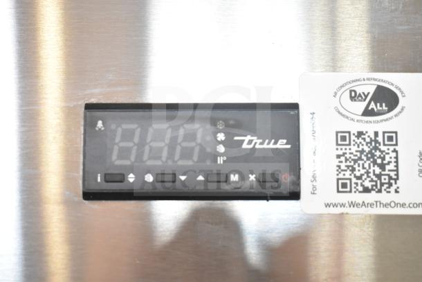 True TSD-33G-HC-LD cooler control panel with logo. Nearby service label includes QR code and contact info.