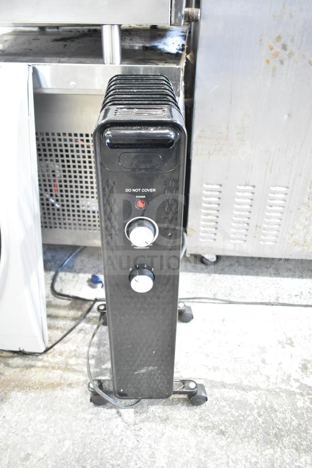 MainStays WSH07O2ABB electric radiator heater, black, temperature control knobs, power indicator light, on wheels.