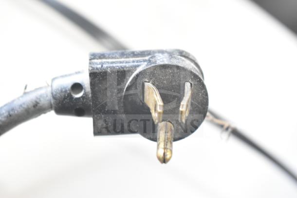 Close-up of a black electrical plug for True TBB-24-60G-SD bar cooler, showing wear and three-prong connection.