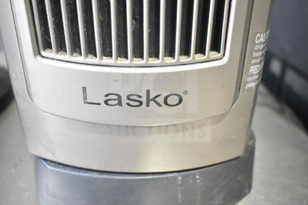 A Lasko heater with visible branding, showing moderate dust on its metal surface.