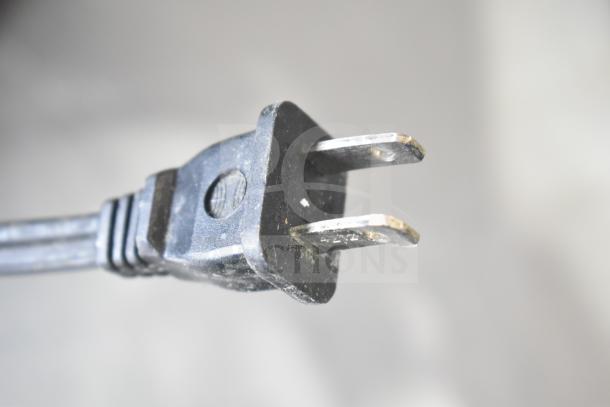 Close-up of a two-prong power plug, possibly from the auction items listed, including Chung Yuan TF-810S fan, Lasko heaters, and Vornado fan.