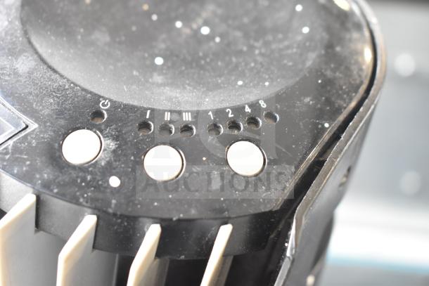 Control panel of a fan with round buttons and speed settings labeled I, II, III, 1, 2, 4, 8. Dust visible on surface.