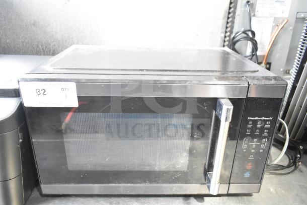 Hamilton Beach HB61B100027880 countertop microwave oven, shows signs of use. Features digital controls, 120 volts, 1 phase.