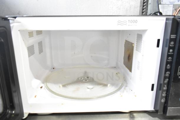 Hamilton Beach HB61B100027880 microwave, 1000 watts, interior view. Shows signs of use, with a glass turntable.