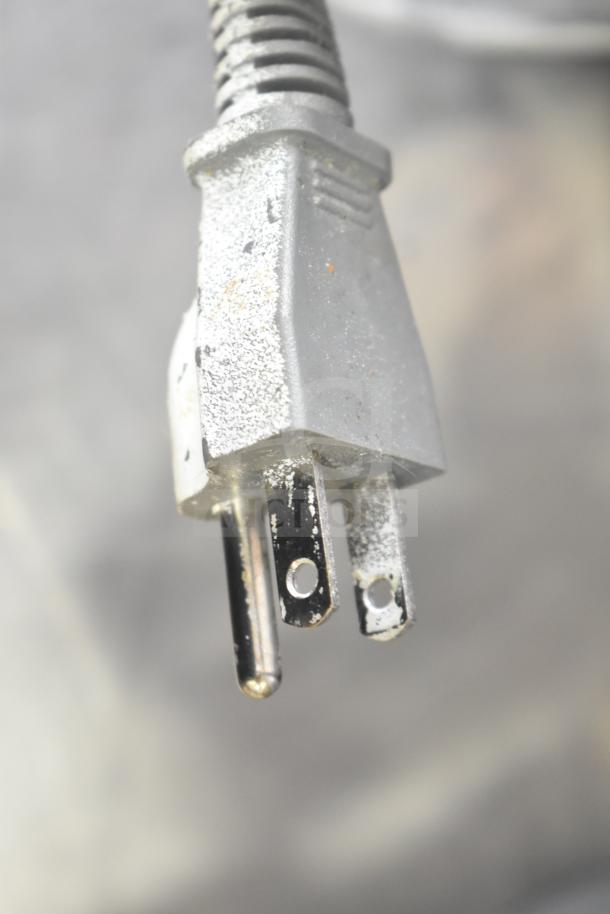 Close-up of a standard three-prong electrical plug, possibly from a Hamilton Beach HB61B100027880 microwave oven.