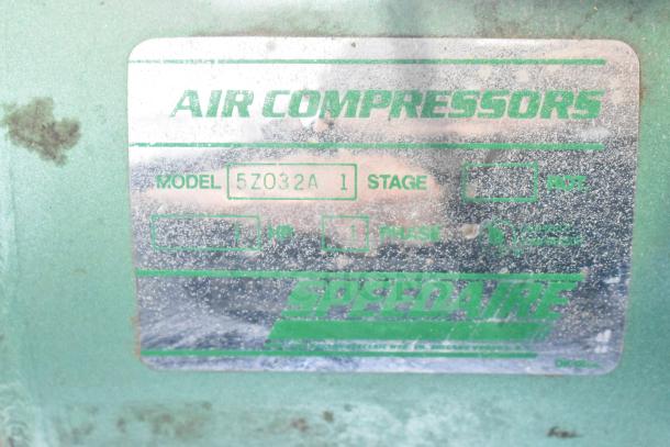 Speedaire 5Z032A Air Compressor label showing model, stage 1, 1 HP, and single phase markings on a green metal surface.