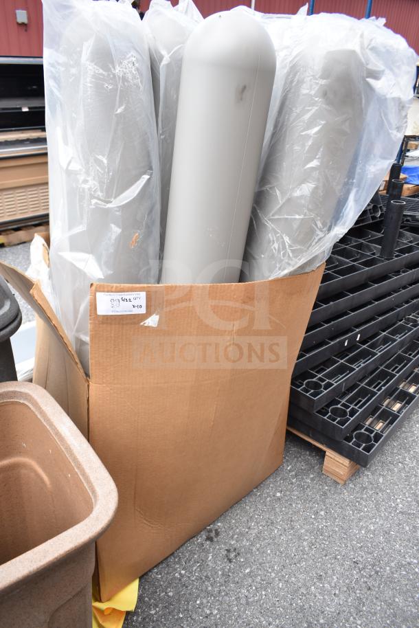 Gray IdealShield bollard covers in a cardboard box, new condition. Tag indicates quantity of 10. Used for protective purposes.