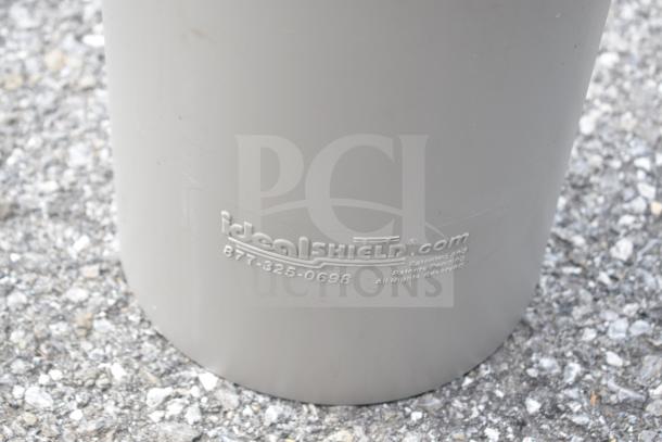 10 IdealShield gray bollard covers, durable, patent-marked, with branding and contact details, on gravel surface.