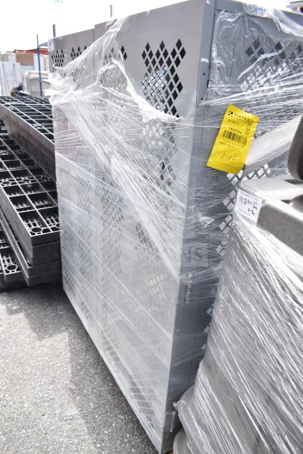 Gray cabinet on commercial casters, wrapped in plastic. Features diamond-shaped ventilation designs. Tag indicates pallet ID.