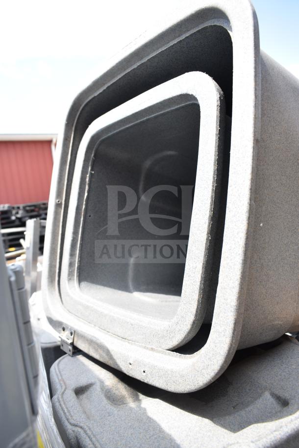 Stacked gray trash cans, various sizes, used condition, durable material. Auction lot of 8. Exterior detail visible.