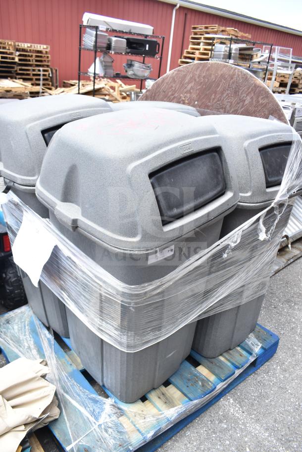 Four gray commercial trash cans with dome lids, stacked on a blue pallet, wrapped in plastic, showing minor wear.