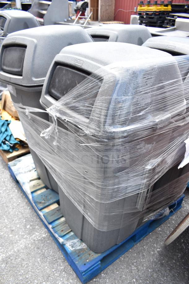 Four gray industrial trash cans shrink-wrapped on a blue pallet, each with a dome lid and opening flap, in good condition.