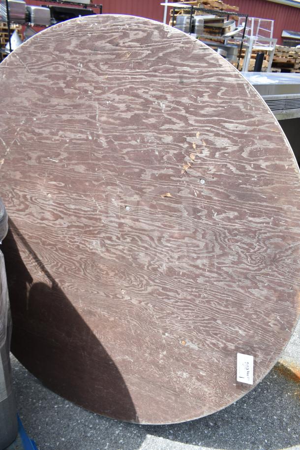 Round folding table, 58x58x3, wooden surface with visible wear and scratches, inventory tag on edge.