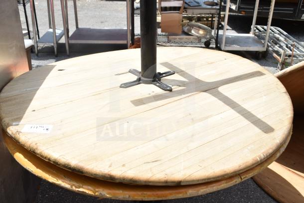 Five-piece auction lot with two round tables and three wooden table tops. Tables show signs of wear.