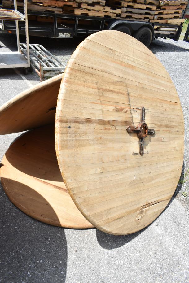 Two wooden tables and three table tops, lightly worn. Includes metal hardware for assembly. Outdoor setting.