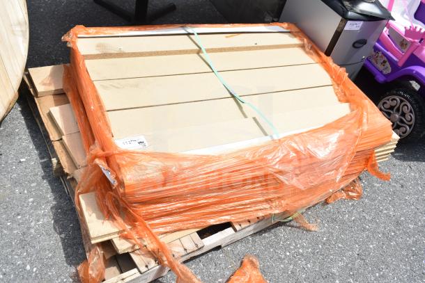 Pallet lot of various items, including secured boards wrapped in orange plastic, and a visible label indicating measurements.
