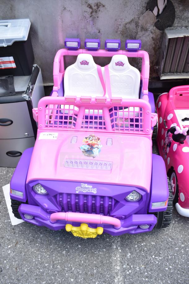 Two children's drive-on vehicles: Disney Princess purple and pink car with character decal, and Minnie Mouse pink car with polka dots.