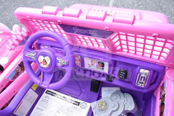 Disney Princess purple and pink children's car interior with steering wheel and dashboard featuring character stickers.