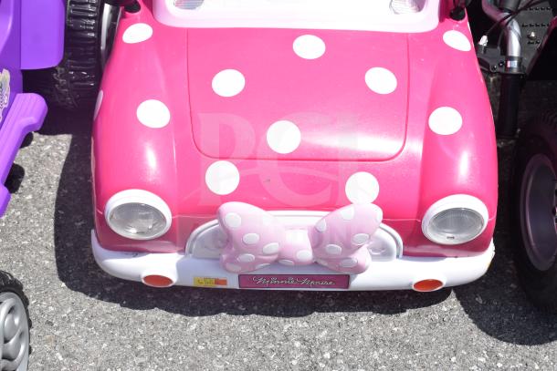 Pink Minnie Mouse children's ride-on car with polka dots and large bow. Disney Princess car partially visible.