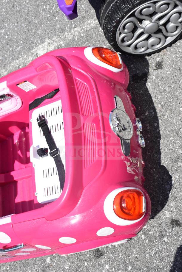 Pink Minnie Mouse children's ride-on car with white polka dots and visible seatbelt; slight wear on rear bumper.